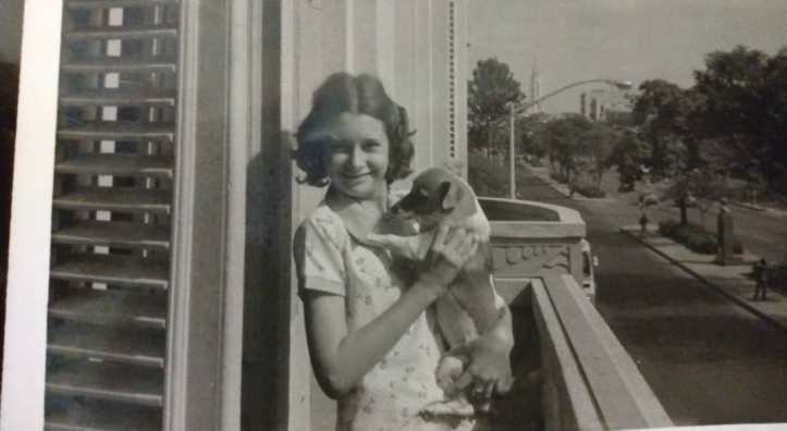 Foto de infancia en blanco y negro de la autora Teresa Dovalpage con su perrita Priscilia, una mezcla de chihuahua y terrier, en un balcón en La Habana.